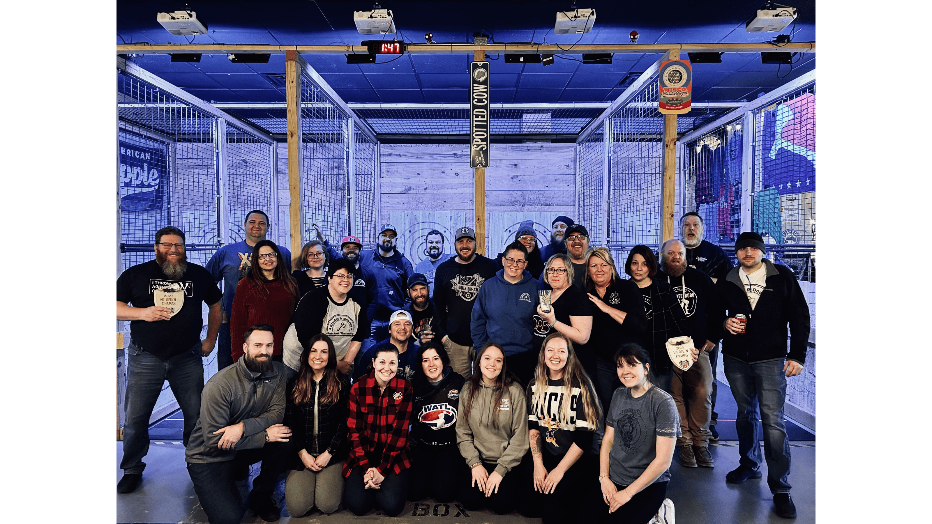 Large group of people posing for a photo at an axe-throwing venue with wooden targets.